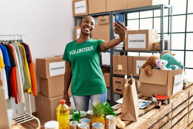 Genç Afrikalı Amerikalı gönüllü kadın gülümsüyor. Yardım merkezindeki akıllı telefondan selfie çekiyor..