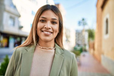 Sokakta kendinden emin gülümseyen genç Latin kadın.