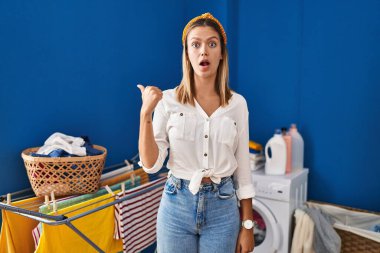 Çamaşırhanedeki genç sarışın kadın elleri yana doğru işaret ederek şaşırdı, ağzı açık hayret içinde kaldı.. 