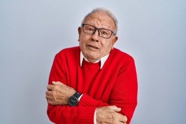 İzole edilmiş arka planda gri saçlı yaşlı adam yüzünde üzgün bir ifadeyle kış soğuğundan titriyor ve donuyor. 