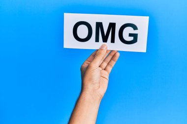 Hand of caucasian man holding paper with omg word over isolated blue background