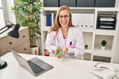 Genç sarışın doktor elinde haplarla mutlu mesut dilini çıkarıyor.. 