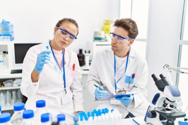 Man and woman wearing scientist uniform working at laboratory