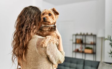 Genç, güzel, İspanyol bir kadın. Köpeğine sarılıyor.