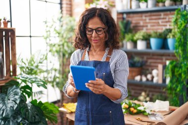 Çiçekçide dokunmatik ped kullanan orta yaşlı bir çiçekçi.
