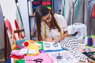 Genç, güzel İspanyol kadın elbise fabrikasında defter çiziyor.