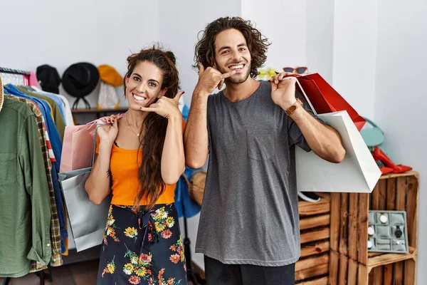 小売店で買い物袋を持っている若いヒスパニック系のカップルは 電話で話すような手や指で電話ジェスチャーをして笑顔 コミュニケーションの概念 — ストック写真