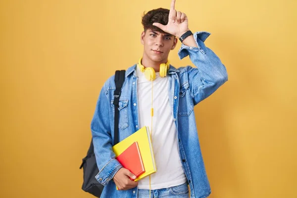Латиноамериканский Подросток Студенческом Рюкзаке Книгами Руках Высмеивает Людей Пальцами Лбу — стоковое фото