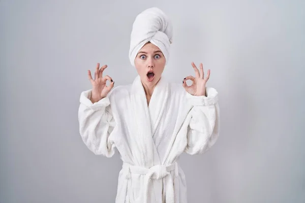 金发女人穿着浴衣 看上去很惊讶 很震惊 用手指做了个认可的标志 疯狂的表达 — 图库照片