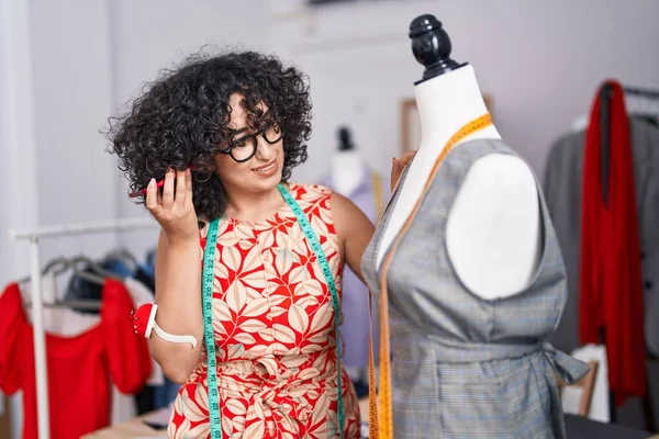 在裁缝店里 年轻的中东女性裁缝通过智能手机测量服装来监听语音信息 — 图库照片