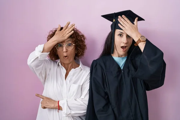 ヒスパニック系の母親と娘の卒業キャップと式のローブを頭の上に手でミスのために驚いて エラーを覚えて着用 忘れられた悪い記憶の概念 — ストック写真