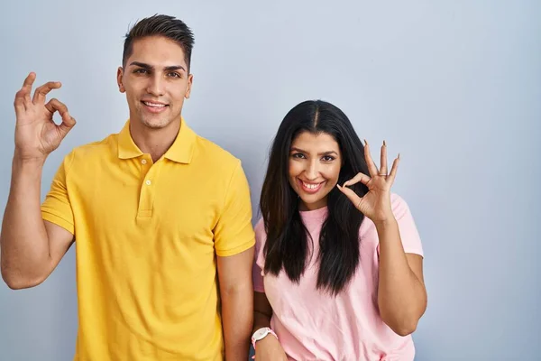 Young Couple Standing Isolated Background Smiling Positive Doing Sign Hand —  Fotos de Stock