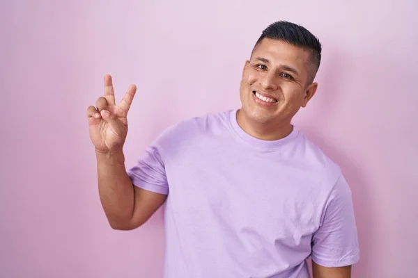 Joven Hombre Hispano Pie Sobre Fondo Rosa Sonriendo Mirando Cámara —  Fotos de Stock