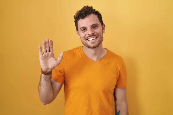 Mladý Hispánec Stojící Nad Žlutým Pozadím Vzdávající Pozdravu Šťastný Usmívající — Stock fotografie