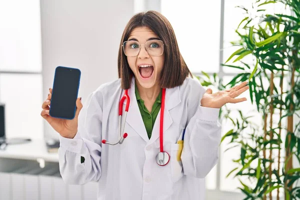 Jovem Mulher Médica Hispânica Mostrando Tela Smartphone Celebrando Vitória Com — Fotografia de Stock