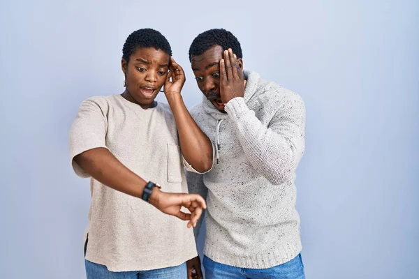 Genç Afro Amerikan Çift Mavi Arka Planda Dikiliyorlar Saatlere Bakıyorlar — Stok fotoğraf