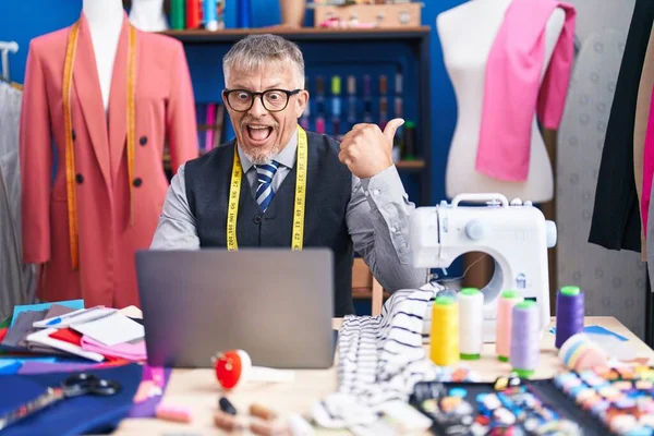 stock image Hispanic tailor man with grey hair doing video call pointing thumb up to the side smiling happy with open mouth 