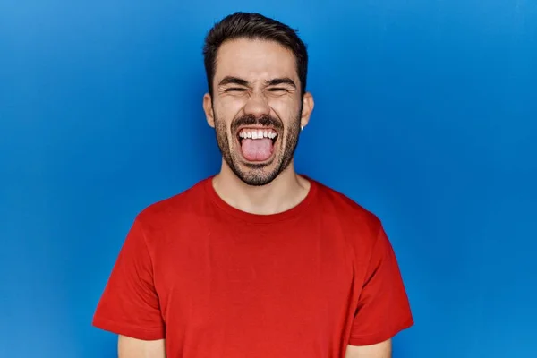 Young Hispanic Man Beard Wearing Red Shirt Blue Background Sticking — Stok fotoğraf