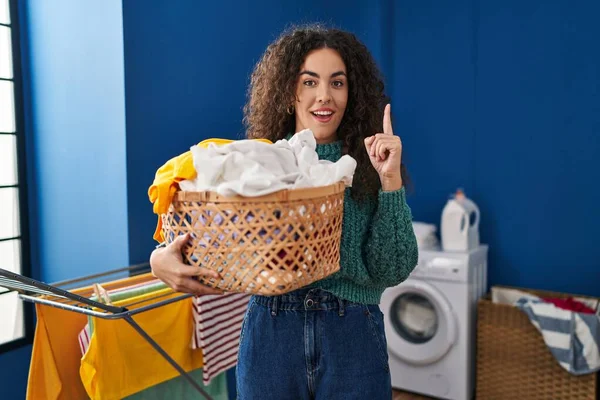 Young Hispanic Woman Holding Laundry Basket Smiling Idea Question Pointing — Stockfoto