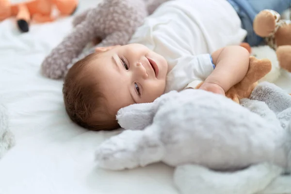 Sevimli Çocuk Yatakta Oyuncak Bebeklerle Gülümsüyor — Stok fotoğraf
