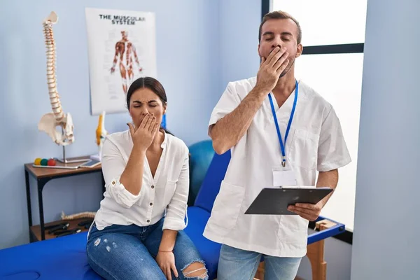 Young Hispanic Woman Physiotherapist Appointment Bored Yawning Tired Covering Mouth — Stockfoto