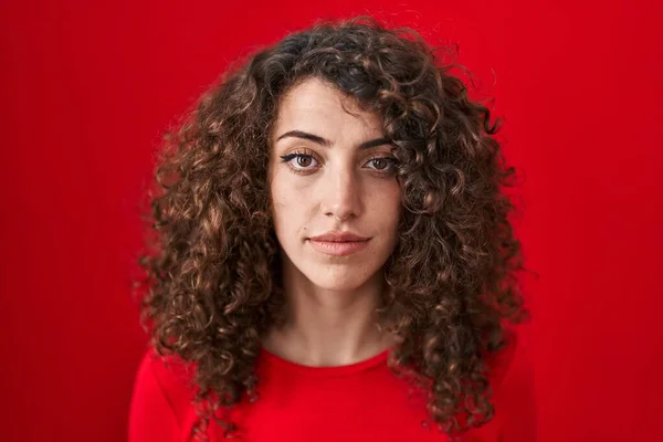 Hispanic Woman Curly Hair Standing Red Background Relaxed Serious Expression — Stok fotoğraf