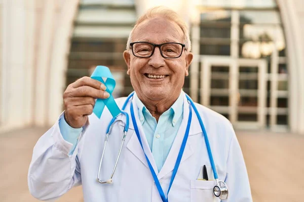 Starší Lékař Šedými Vlasy Drží Modrou Stuhu Vypadá Pozitivně Šťastně — Stock fotografie