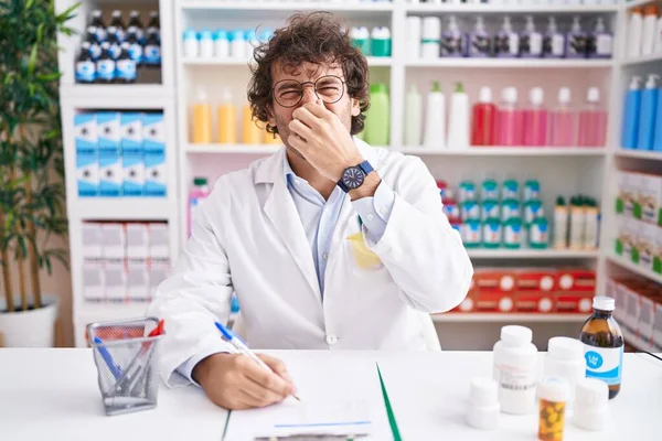 薬局で働くヒスパニック系の若者は臭いと嫌な匂いを嗅ぎ鼻に指で息をしている 臭いが悪い — ストック写真