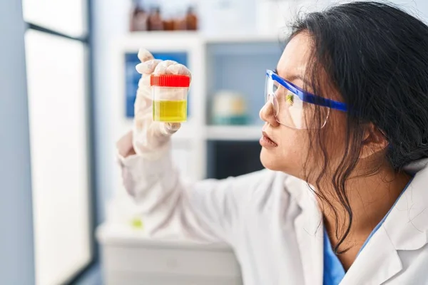 穿着科学家制服的中国年轻女子拿着尿检试管在实验室里 — 图库照片