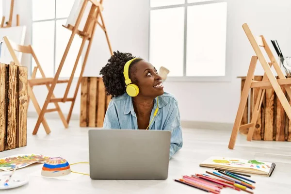 在艺术工作室使用笔记本电脑和耳机的年轻非洲裔美国女艺术家 — 图库照片