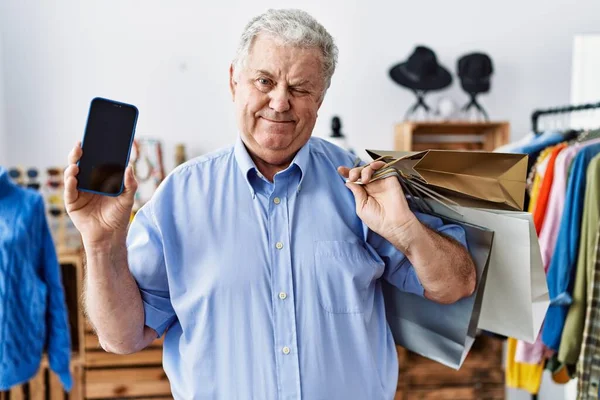 Senior Man Med Grått Hår Håller Shoppingväskor Och Visar Smartphone — Stockfoto