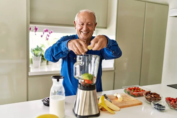 Hombre Mayor Sonriendo Confiado Poniendo Plátano Licuadora Cocina —  Fotos de Stock
