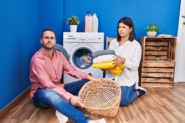 家で洗濯をする若いカップルは懐疑的で緊張し 問題のために動揺を眉をひそめています 否定的な人 — ストック写真