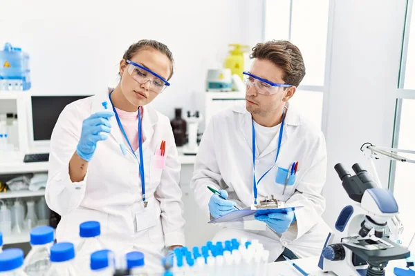 Man and woman wearing scientist uniform working at laboratory