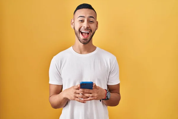 Hombre Hispano Joven Usando Mensaje Escritura Teléfonos Inteligentes Celebrando Loco —  Fotos de Stock