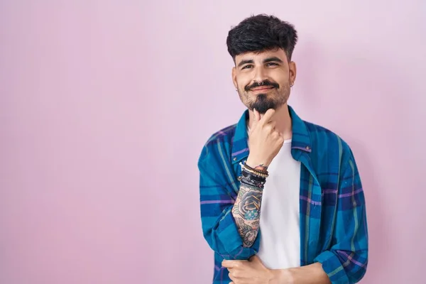 Joven Hombre Hispano Con Barba Pie Sobre Fondo Rosa Mirando —  Fotos de Stock
