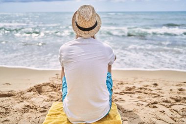 Genç kızıl saçlı turist plajda havlunun üzerinde oturuyor..