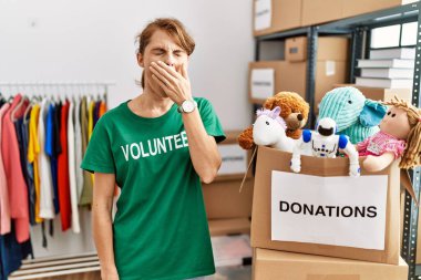 Bağışta gönüllü tişört giyen beyaz güzel bir kadın elleriyle ağzını kapatmaktan sıkılmış. Huzursuz ve uykulu.. 