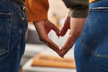 Erkek ve kadın yeni evlerinde kalp sembolü yapıyorlar.