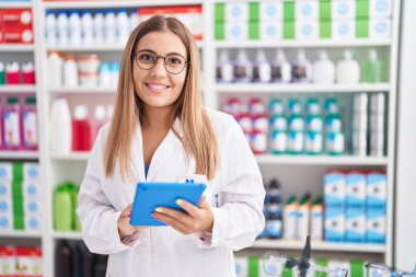 Eczanede çalışan dokunmatik ped kullanan genç, güzel İspanyol kadın eczacı.