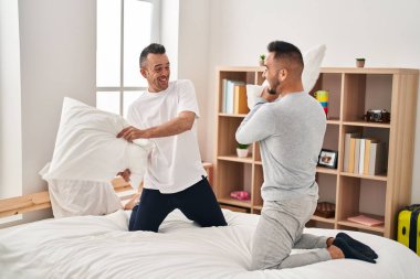 Two men couple fighting with pillows at bedroom