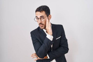 Handsome business hispanic man standing over white background hand on mouth telling secret rumor, whispering malicious talk conversation 