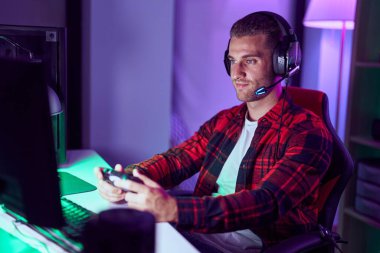Young caucasian man streamer playing video game using joystick at gaming room