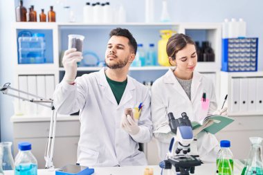 Man and woman wearing scientist uniform working at laboratory