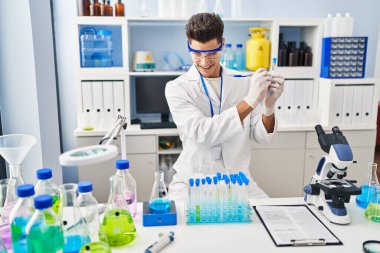 Laboratuvarda test tüpünde yazan bilim adamı üniforması giyen İspanyol genç adam.