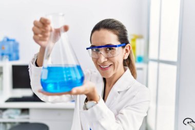 Laboratuvarda deney tüpü tutan bilim adamı üniforması giyen İspanyol genç bir kadın.