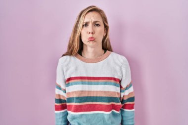 Pembe arka planda duran genç sarışın kadın depresif ve endişeli, sinirli ve korkmuş bir şekilde ağlıyor. hüzünlü ifade. 