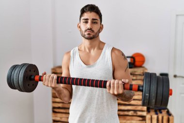 Yüzünde ciddi bir ifade olan, ağırlıklı, genç İspanyol adam eğitimi almış. Basit ve doğal bir şekilde kameraya bakıyorsun.. 