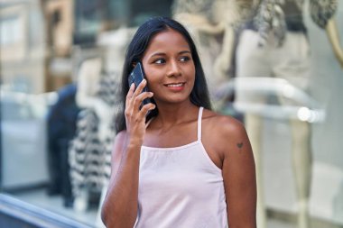 Genç, güzel bir kadın, gülümsüyor. Kendine güveniyor. Akıllı telefondan konuşuyor.