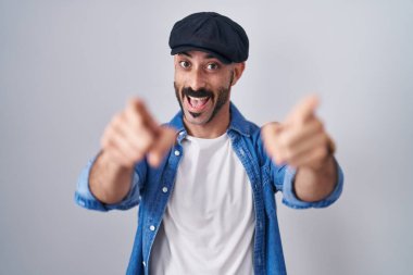 Sakallı İspanyol bir adam tecrit edilmiş arka planda seni ve kamerayı işaret ediyor, gülümsüyor, pozitif ve neşeli. 